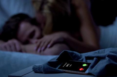 woman cuddlig up to sleeping man while wife calls phone