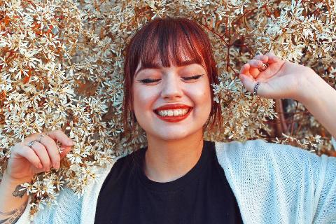 woman laying in bed of white flowers and smiling with eyes closed