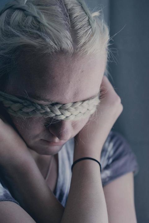 woman uses braids to hide her eyes with her hands