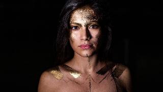 A woman with gold painted on her face and body.