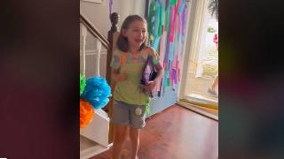 A little girl walking into a house, smiling.