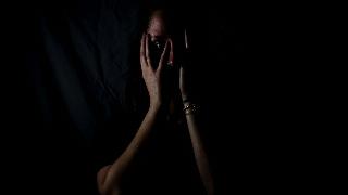 woman hiding her face on black background