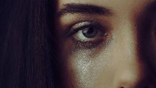 close up of sparkly tear on woman with smudged makeup