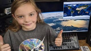 little girl gives thumbs up by space computer station