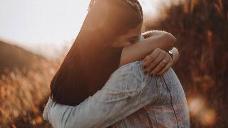 man and woman hug in field