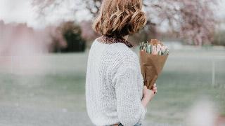 woman holding flower bouquet at the park facing back