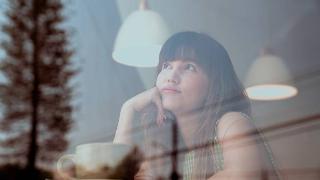 woman thinking with her hand on her cheek at coffee shop