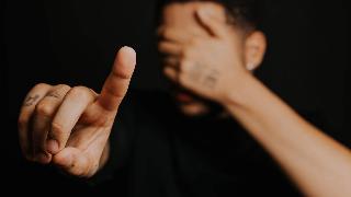 a-person-pointing-fingers-while-covering-his-eyes on dark background