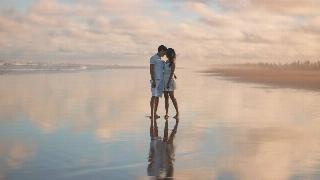 photo-of-couple-standing-on-water-with sky reflecting on sand