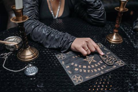 woman-in-black-long-sleeves-using-an-ouija-board-