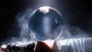 A crystal ball on a table with smoke behind it.