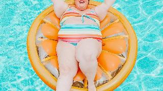 fran in pool on an orange floatie with arms up