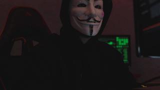 person in hoodie and anonymous mask sits at computer with code