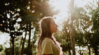 side-view-portrait-photo-of-woman-in-yellow-t-shirt-standing-with-her-eyes-closed-with-trees-in-the-background