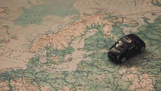 A small toy car placed atop a map, just below the Nordic nations.