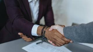 Two people shaking hands at what appears to be a job interview.