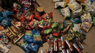 A ;arge dumpster diving haul of bagged and boxed food stacked on someone's floor.