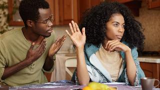 Unhappy African American male cheater holding hand on his chest apologizing to beautiful indifferent woman who ignoring and refusing all his excuses, telling him to get lost.