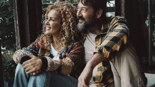 Couple man and woman mature age enjoy and relax together at home sitting on the floor and looking outside the window.