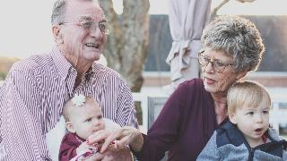 Two grandparents holding two young grandkids in their laps.