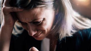 A woman clutching her own head while crying.