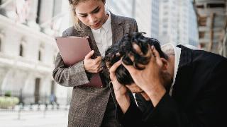 A business woman comforting a male colleague.