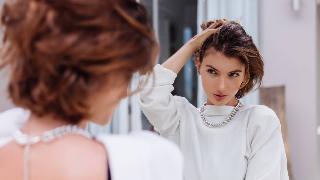 A young woman admiring herself in a mirror.