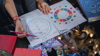 A woman sitting at a table mapping out an astrological chart.