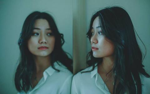 A girl looking at a reflection of herself on a seamless mirror.