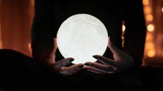 Someone holding a moon light in their hands.