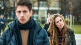 A man walking away from a woman who's belittling him.