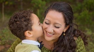 A young boy kissing his mother on the cheek.