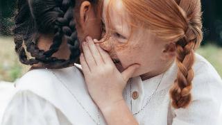 A little girl telling her friend a secret.