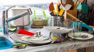 A kitchen sink and counter covered in dishes.