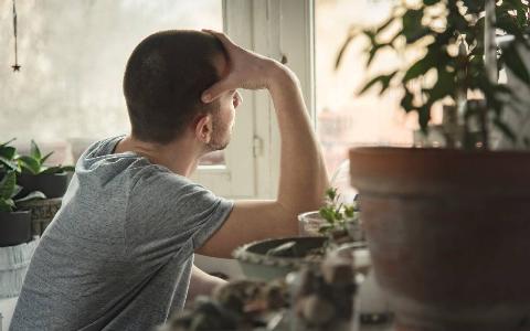 A man looking out his window forlornly.