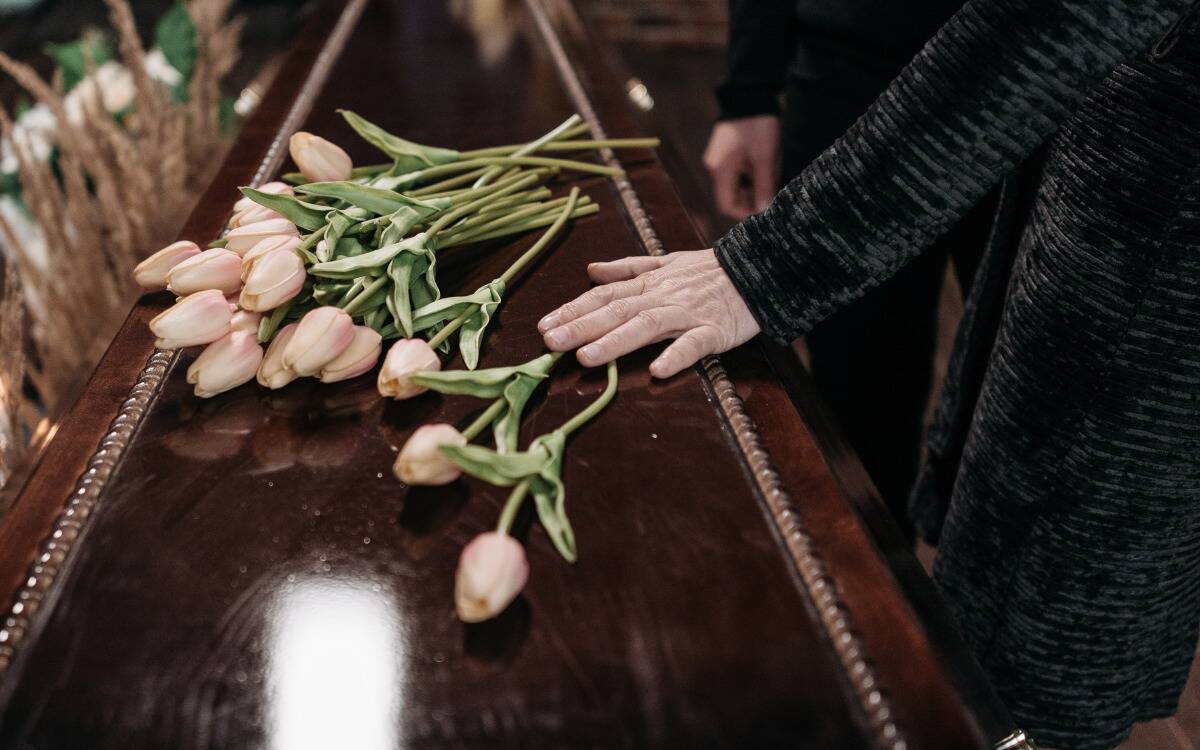 People placing flowers atop a coffin.