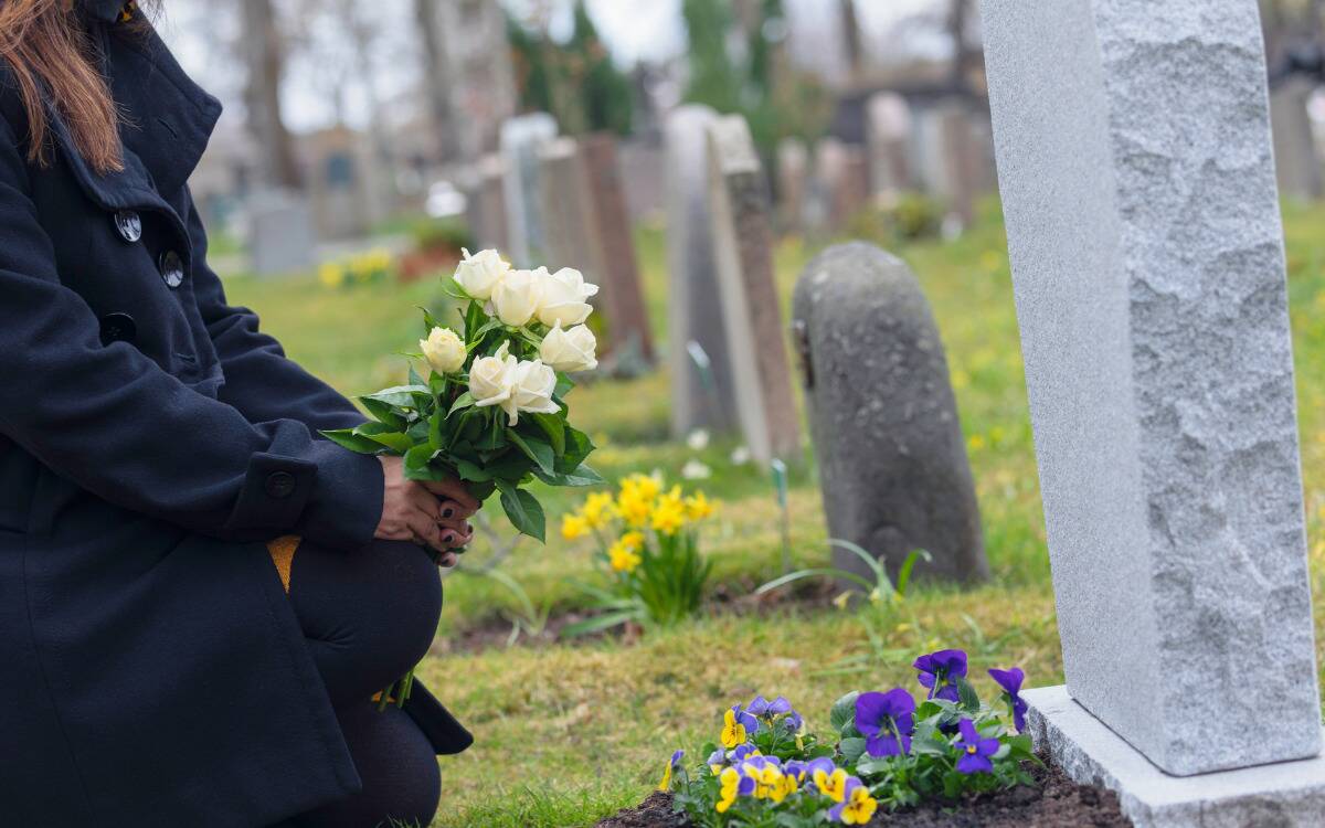 A woman laying flowers on a grave.