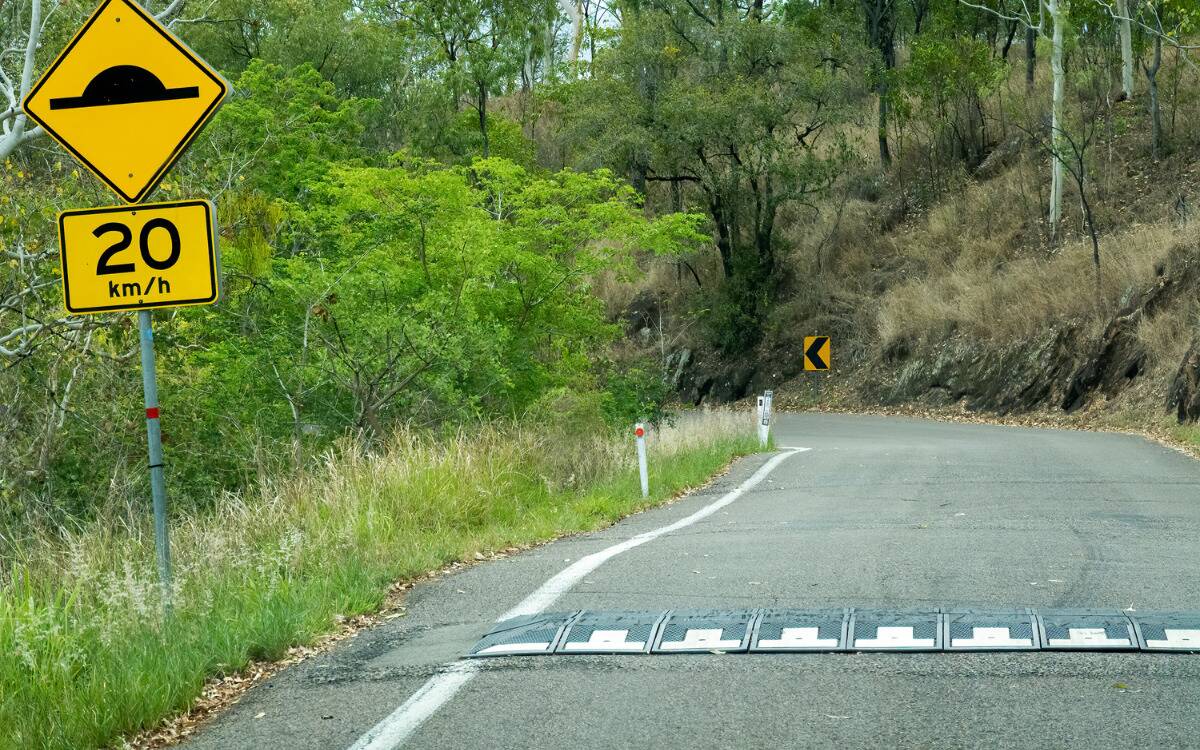 A speedbump on the road, including a sign indicating their presence on the side.