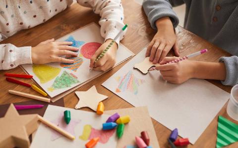 Kids drawing and making crafts around a table.