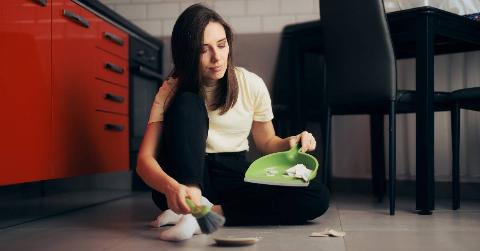 A woman sweeping up pieces of broken ceramic.