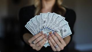 A woman fanning out $100 bills in front of her.