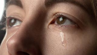 A closeup of someone's eyes, a tear falling from one.