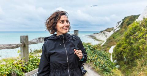 A woman on a solo journey by a beach/cliffside.