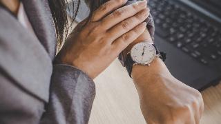 A woman pushing she sleeve up to check her watch. 