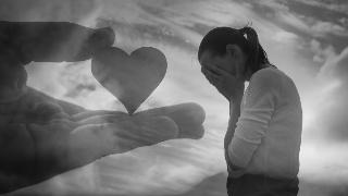 A greyscale image of a woman with her head in her hands, while a superimposed hand holding a hart is positioned next to her.