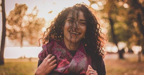 A woman smiling as she walks outside.