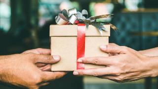 Two pairs of hands exchanging a gift box.