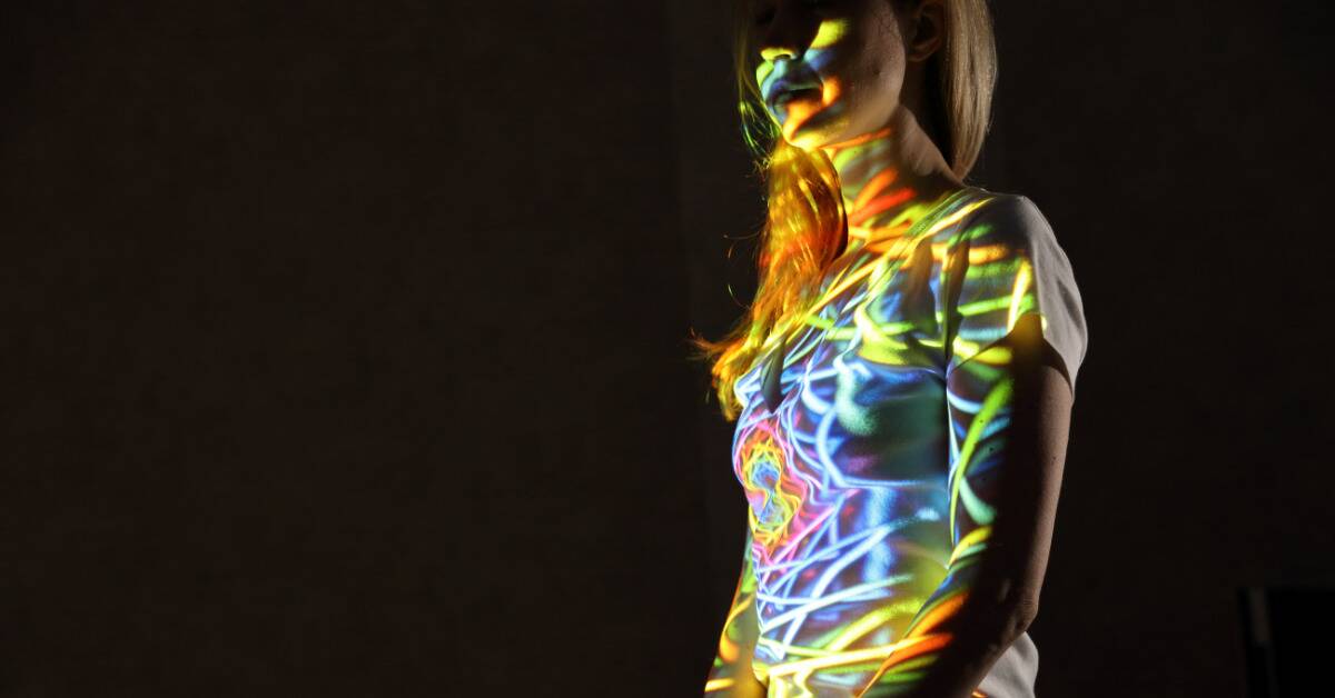 A woman with a rainbow mandala being projected onto her.