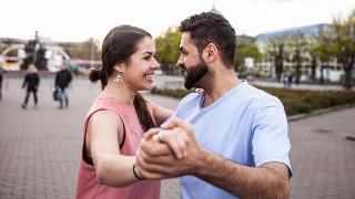 A couple waltzing in public, both smiling.