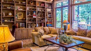 A family living room with a very large shelving unit in the back, every shelf full of stuff.